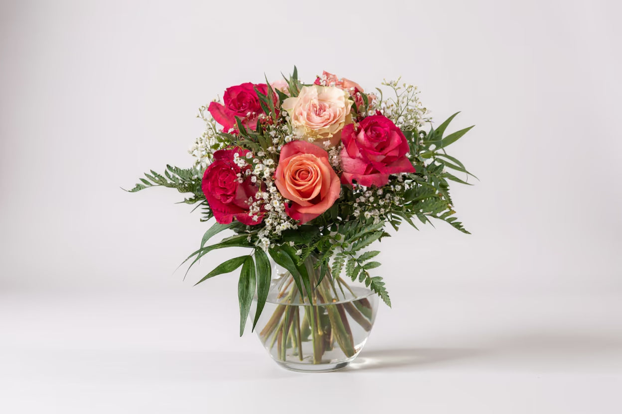 Blumenstrauß in Rosa Tönen in grüner Vase vor hellem Hintergrund